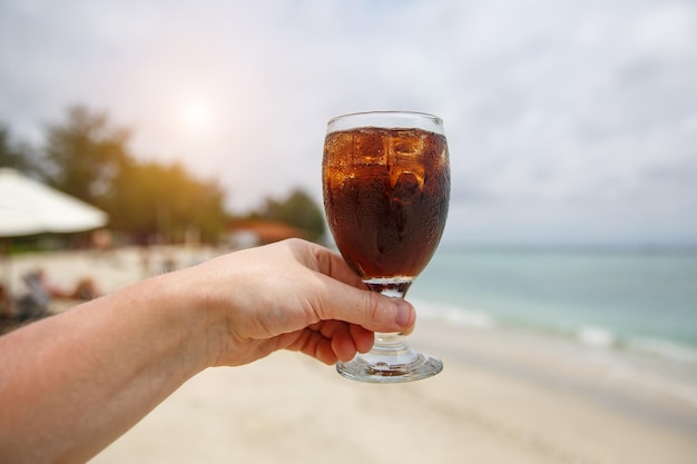 Bevanda rinfrescante in mano sulla spiaggia