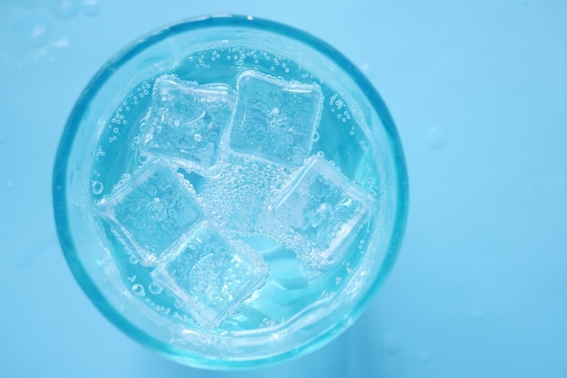 Bevande analcoliche in un bicchiere con cubetto di ghiaccio su sfondo blu