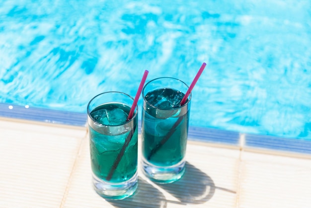 Bevande analcoliche refrigerate due cocktail blu con ghiaccio vicino alla piscina in una giornata di sole