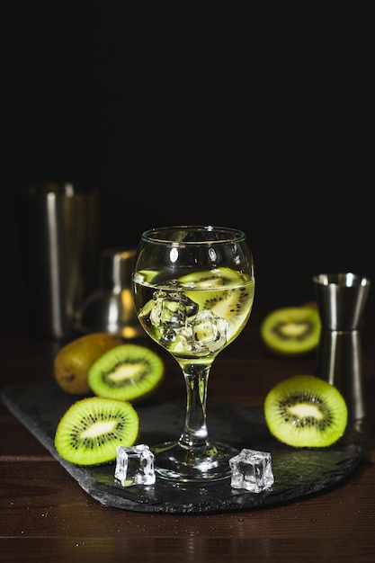 Bevande e bevande fredde estive Cocktail alcolico con kiwi e ghiaccio in bicchiere di vino su sfondo nero