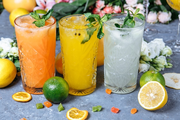 Bevande fresche estive bevande fredde limonata ghiacciata nella brocca e limoni e arancia con menta sul tavolo all'aperto limonata all'arancia in un bicchiere