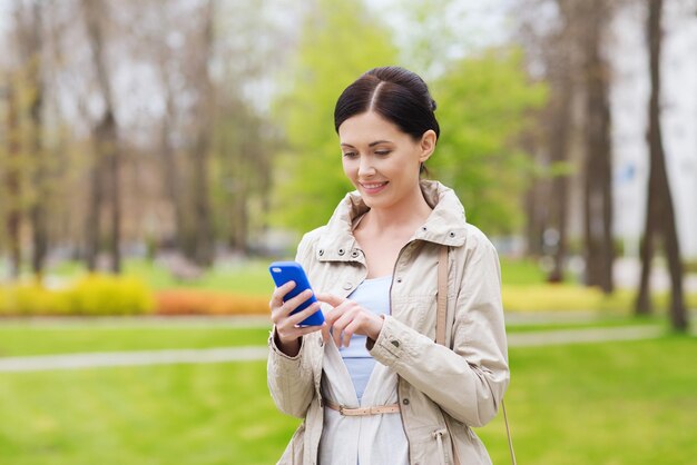 bevande, tempo libero, tecnologia e concetto di persone - donna sorridente che chiama e parla sullo smartphone nel parco