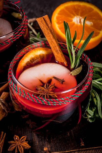 Bevande tradizionali invernali e autunnali. Cocktail di Natale e del Ringraziamento. Vin brulè con arancia, mela, rosmarino, cannella e spezie su uno sfondo di pietra scura, copia spazio vista dall'alto