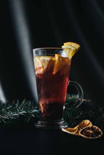 Bevande tradizionali invernali e autunnali. Cocktail di Natale e del Ringraziamento. Vin brulè con arancia, mela, rosmarino, cannella e spezie su uno sfondo di pietra scura, copia spazio vista dall'alto