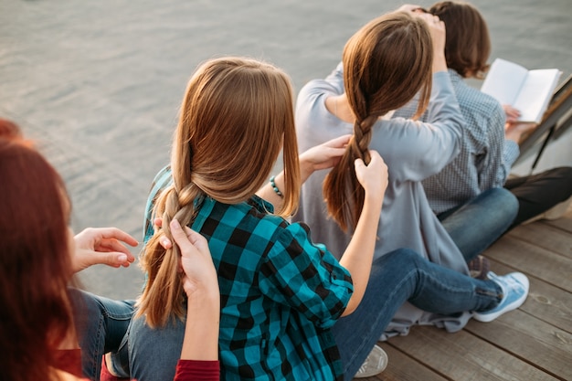 Bff supporta la cura dell'amicizia. Le ragazze si intrecciano i capelli. Concetto di lavoro di squadra