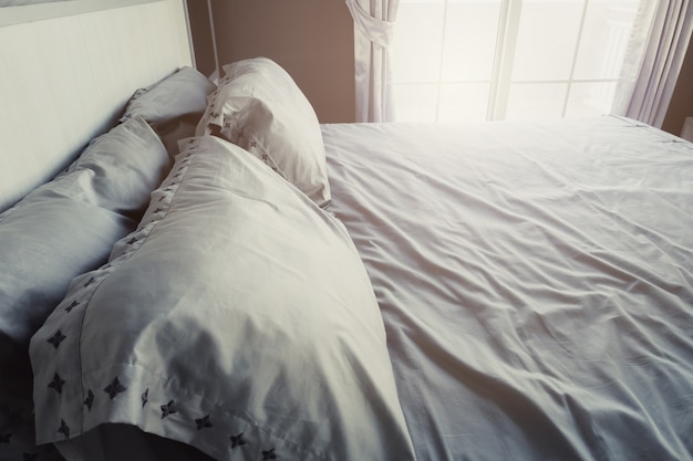 Biancheria da letto con cuscini e lenzuola bianche in camera di bellezza.