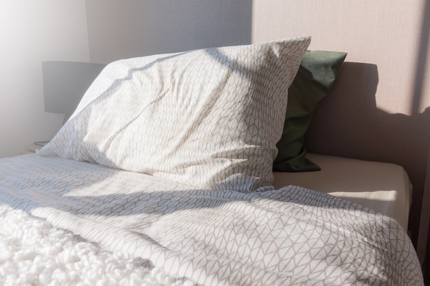 Biancheria da letto con cuscini e lenzuola bianche in camera di bellezza.