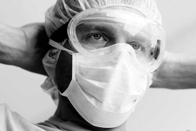 Bianco e nero. Ritratto del primo piano Il lavoratore medico nella maschera protettiva prepara per lavoro.