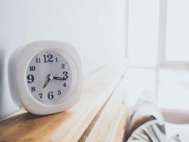 Bianco semplice orologio sul loft woden letto al mattino.