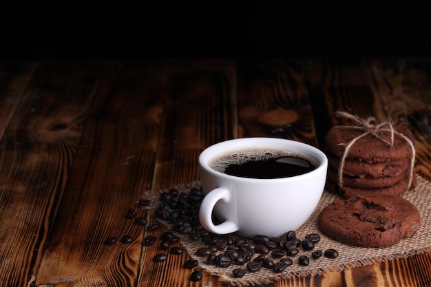 Bianco tazza di caffè americano con biscotti al cioccolato sul tavolo di legno vintage scuro