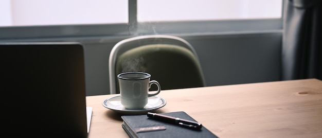 Bianco tazza di caffè caldo notebook e computer portatile sulla tavola di legno