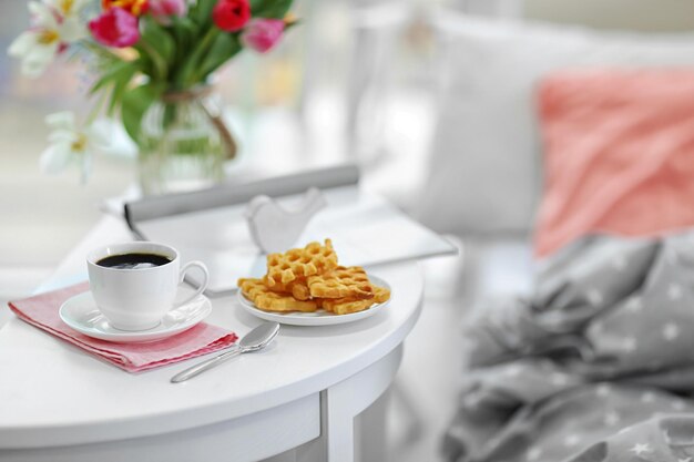 Bianco tazza di caffè e dolci sul tavolo di legno in una stanza luminosa