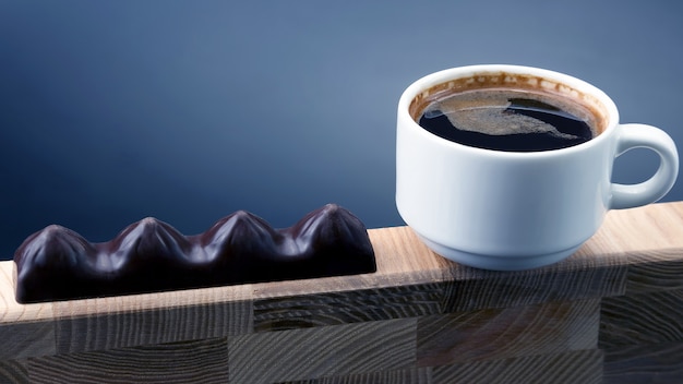 Bianco Tazza di caffè nero con cioccolato su una cornice di legno. cibo da dessert