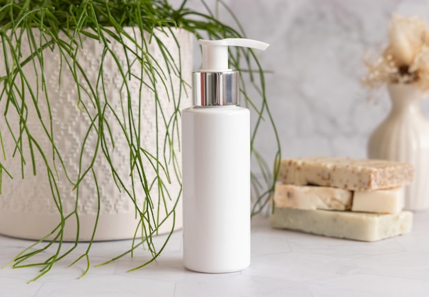 Bianco vuoto una pompa bottiglia cosmetica su marmo vicino pianta verde close-up mockup