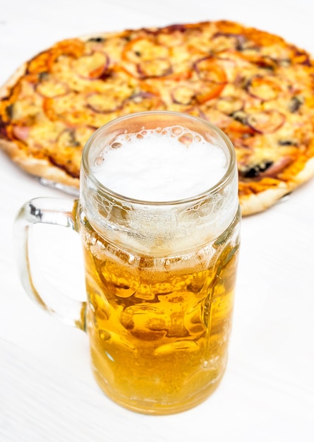 Bicchiere con birra e pizza al forno sul tavolo bianco