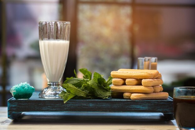 Bicchiere con erbe liquide bianche e biscotti su vassoio menta profumata e latte fresco ingredienti d'italia...