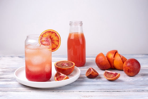 Bicchiere con rinfrescante limonata all'arancia sanguinante, acqua di agrumi di frutta estiva su un bianco