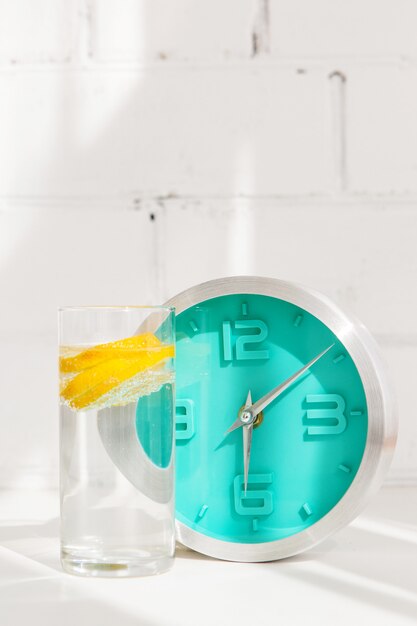 Bicchiere d'acqua con limone e orologio