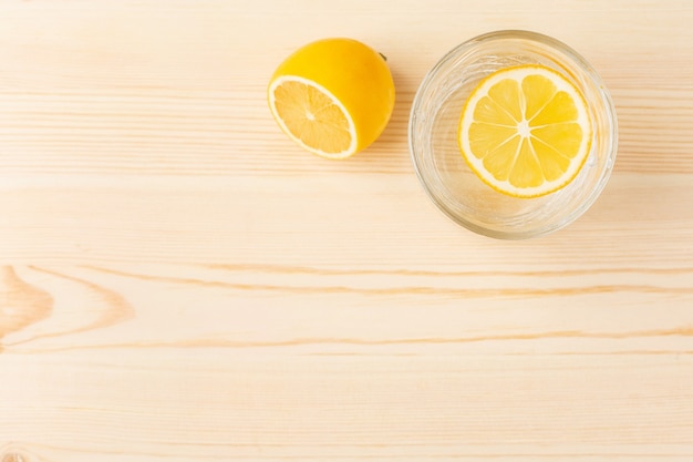 Bicchiere d'acqua con limone su un tavolo di legno con copyspace, bevanda mattutina per uno stile di vita sano