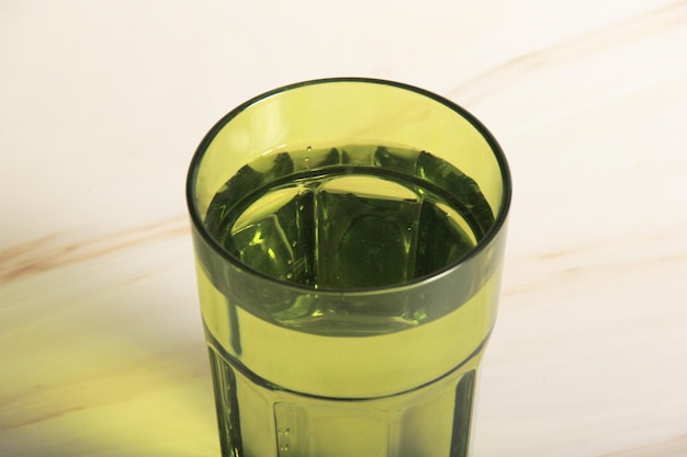 bicchiere d'acqua e uno sfondo chiaro con foglie di piante