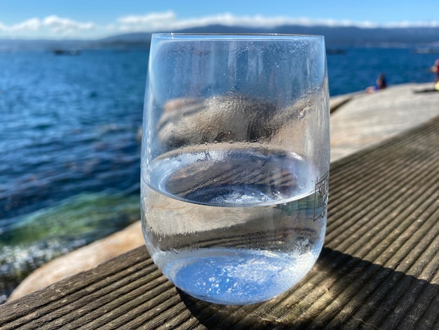 Bicchiere d'acqua fredda in riva al mare in una calda giornata estiva