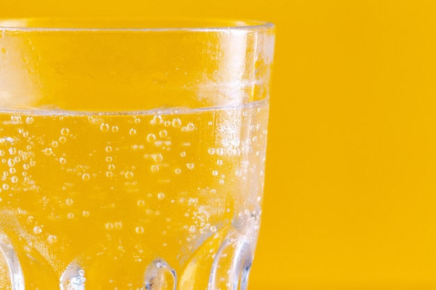 Bicchiere d'acqua su fondo giallo. Uno stile di vita sano