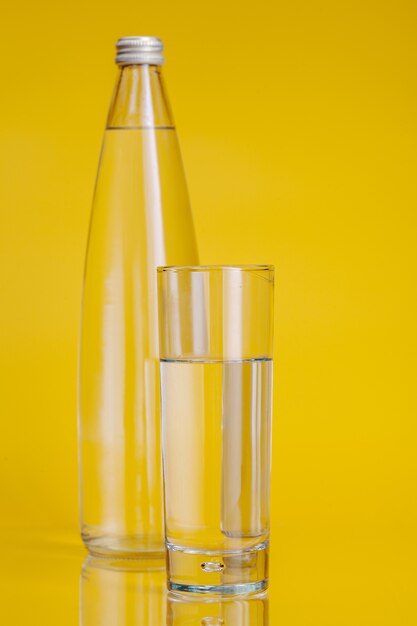 Bicchiere d'acqua su fondo giallo. Uno stile di vita sano