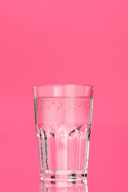 bicchiere d'acqua su uno sfondo rosa