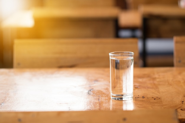 Bicchiere d&#39;acqua sul banco di legno