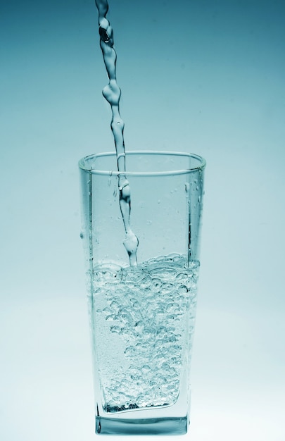 Bicchiere d'acqua versando con la riflessione