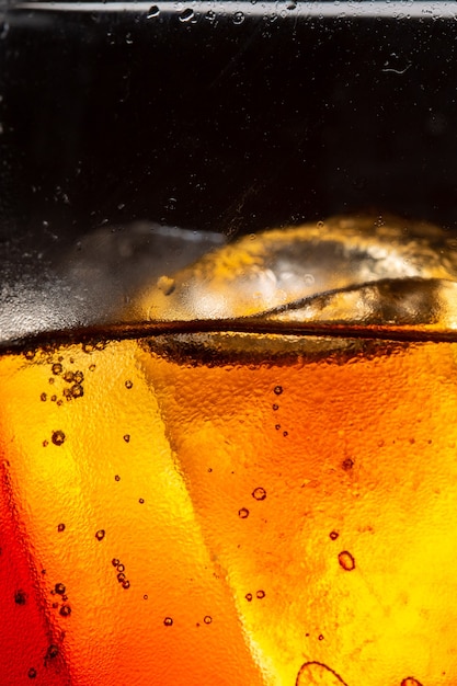 Bicchiere da bibita con spruzzi di ghiaccio su sfondo scuro Bicchiere da cola nel concetto di festa celebrativa