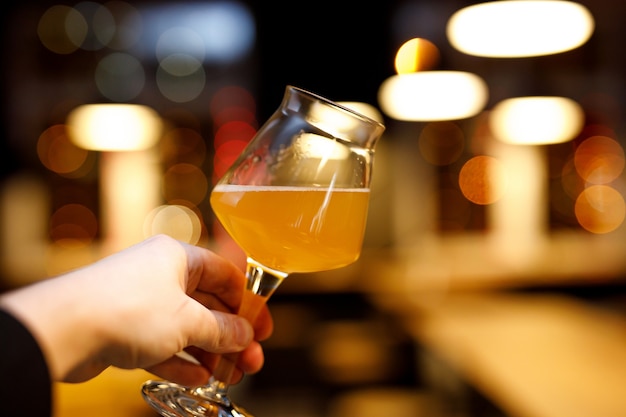 Bicchiere da birra con una gamba sottile in mano. Sfocata sullo sfondo della barra