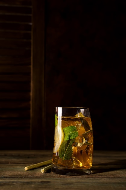 Bicchiere da cocktail con ghiaccio, menta e zenzero su un backgorund in legno scuro