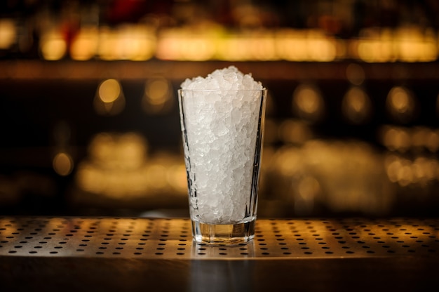 Bicchiere da cocktail con limonata di ghiaccio tritato in piedi sul supporto vuoto della barra d'acciaio