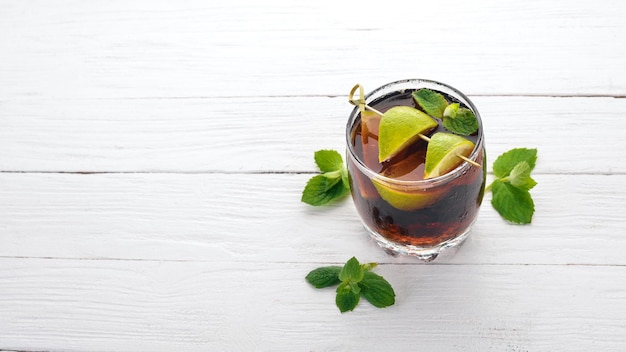 Bicchiere da cocktail Cuba libre Lime menta Su uno sfondo di legno bianco Spazio libero per il testo