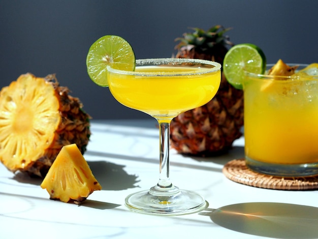 Bicchiere da cocktail estivo con ananas fresco e luce solare diretta al lime