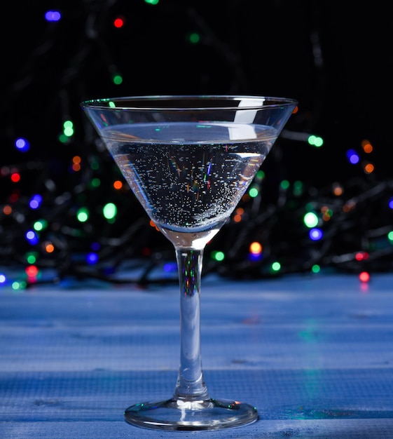 Bicchiere da cocktail su luci colorate ghirlanda sfocati. Cocktail alcolico per la festa invernale. Concetto di idee cocktail. Ricette facili per cocktail alcolici invernali. Cosa bere alla festa di natale.