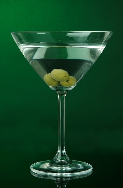 Bicchiere da Martini con olive su sfondo verde scuro