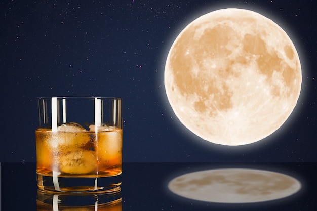 Bicchiere da whisky sul cielo di mezzanotte con sfondo di luna piena. Bicchiere da cognac. Bicchiere di brandy. Cognac Francia. Luna piena e bevanda scozzese. Luna piena nel cielo notturno. Luna mistica piena.