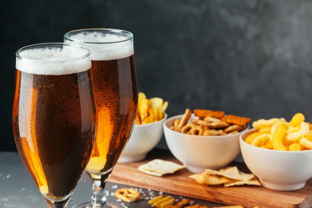 Bicchiere di birra chiara con ciotole snack