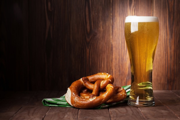 Bicchiere di birra chiara e pretzel sul tavolo di legno. Visualizza con copia spazio