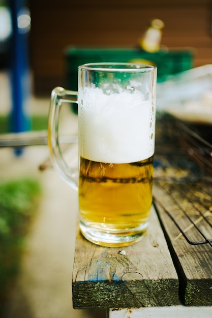bicchiere di birra con schiuma sul tavolo in giardino