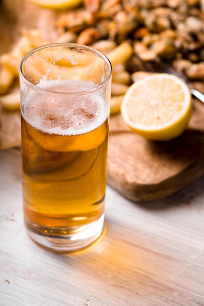 Bicchiere di birra con spuntino sfocato sul tavolo di legno bianco