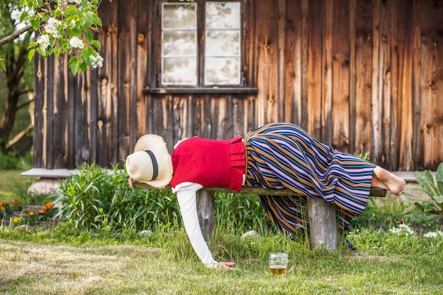 Bicchiere di birra e donna che dorme su una panchina, Ligo