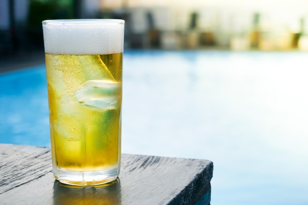 Bicchiere di birra leggera sul tavolo di legno in piscina