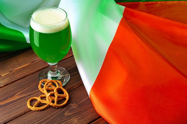 Bicchiere di birra verde contro la bandiera dell'Irlanda da vicino