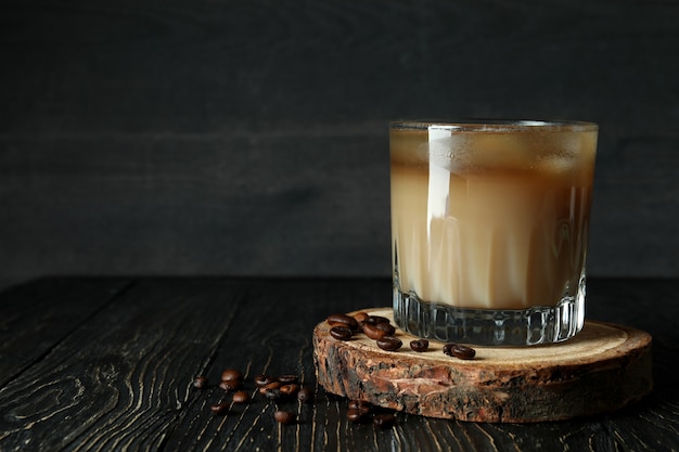 Bicchiere di caffè freddo e fagioli sul tavolo di legno