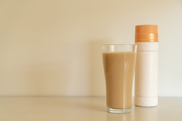 Bicchiere di caffè latte con bottiglie di caffè pronte da bere sul tavolo