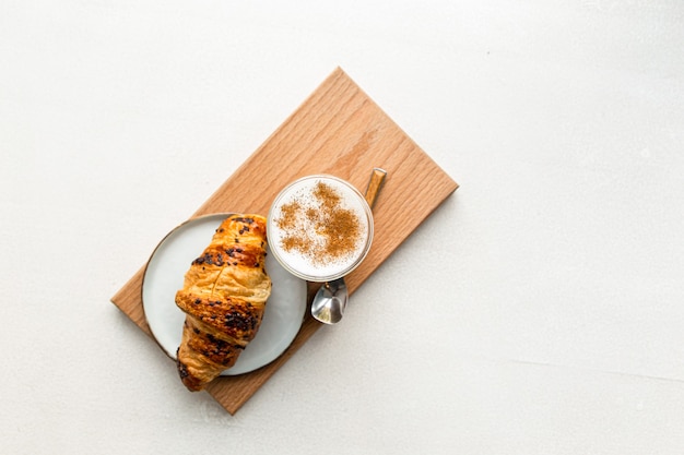 Bicchiere di caffè latte con cannella e croissant