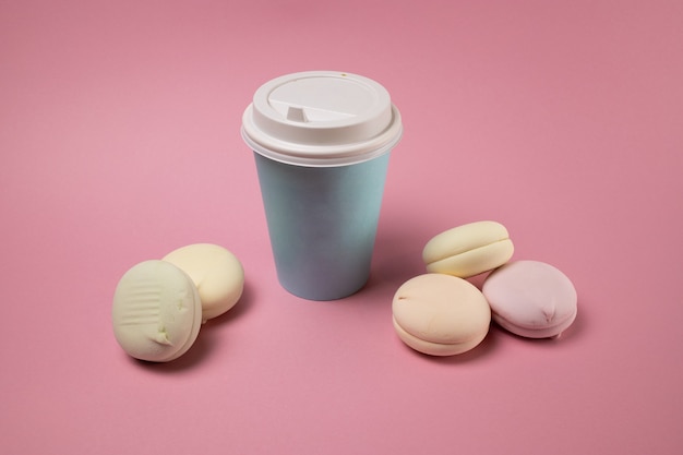 Bicchiere di carta di caffè e macarons su uno sfondo rosa